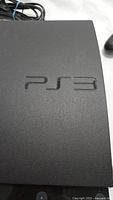 Close up of PS3 console top showing embossed PS3 logo in matte black finish.