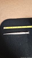 Full length photo of Yard-o-Led silver pencil placed next to measuring tape showing 5 1/8 inch length.