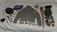 Full view of all items spread on bed: grey Wolf Cub shirt with badges, hats, various badges, ties, and pins