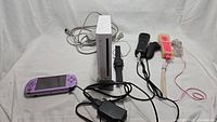 Overview of all included items: Wii console with accessories, two remotes with sleeves and nunchuks, and purple PSP