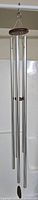 Full view of the large wind chime showing four metal tubes and wooden hanging top.