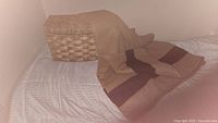 Tan wool blanket with dark brown stripes draped over a woven wicker basket, displaying texture and size.