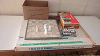 Photo showing all items on a table including chessboards, boxes of chess pieces, playing cards, and boxed Rummoli game