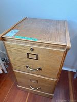 Full view of the wooden filing cabinet showing two drawers with metal handles and label holders.