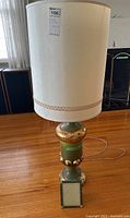 Photo showing the full lamp from front including lampshade and base on hardwood floor.