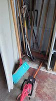 View of assorted gardening tools including rakes, shovels, and snow shovel in garage corner