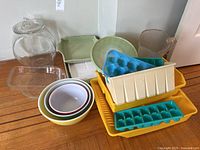 Full lot of Pyrex kitchenware, mixing bowls in stacked arrangement, glass bakeware, plastic ice trays, and other kitchen containers