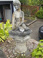 Full view of mermaid statue on pedestal in front garden