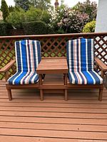 Front view of connected wooden chairs with center table and striped cushions on deck