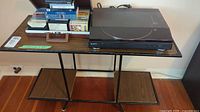 Wide view of retro metal and wood table holding a collection of cassette tapes and Sony turntable