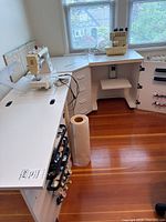 Full view of all three white sewing table units assembled in L-shape with sewing machine and serger on top