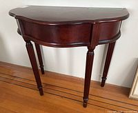 Side half table showing front curved shape, fluted legs, and polished mahogany finish.