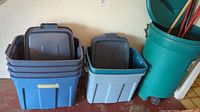 Stack of blue plastic storage containers with lids inside one another, next to a green garbage bin.