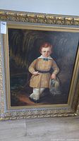 Full view of oil painting in ornate gilt frame showing portrait of a young boy