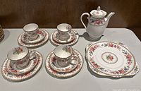 Full view of the Royal Grafton bone china set showing four teacups with matching saucers, teapot, and serving plate.