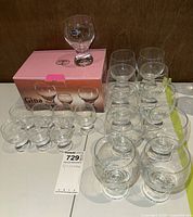 Set of 15 Bohemia Gina stemless glasses arranged on table with the original pink box behind them. One glass on top of the box shows Bohemia logo sticker.