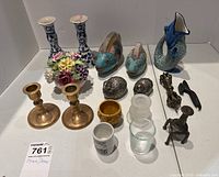 Showing full assortment of decorative items including ceramics, brass candlesticks and figurines, flower arrangement, and glass candle holders