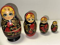Four of the nesting dolls lined up from largest to smallest on a white surface.