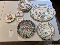 Entire serveware set with large platter, soup tureen with lid, round plates, and small dishes showing floral designs.