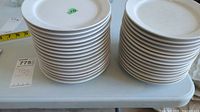 Two stacks of white side plates showing the quantity and condition, visible crazing and chips on some plates.