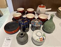 Full lot of assorted teacups, saucers, teapots, and decorative jars on table