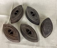 Five cast iron antique sad irons arranged on cloth with surface rust and embossed brand and model text visible