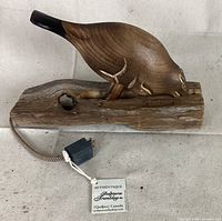 Image of a wooden beaver door knocker carved with detailed features and mounted on a natural wood log base with drill hole, includes authenticity tag for Tremblay Sculptures Quebec Canada.