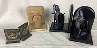 Image showing all four bookend pieces: two copper bookends with round embossed medallions, two black metal horse on wood bookends, and one single carved wood bookend block.