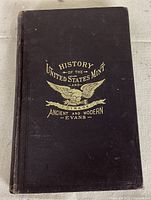 Front cover of the book showing gilt embossed title and eagle emblem on dark cover.