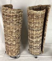 Two tall rolled wicker lamps shown upright from front view looking down on black metal ball feet bases