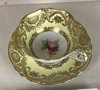 Top view showing the detailed gold floral pattern on yellow background inside cup with pink rose center on cup and saucer