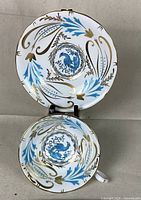 Top view of teacup placed on matching saucer showing detailed blue and gold painted peacock and floral design