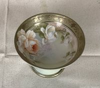 Top angled view of pedestal bowl showing floral and gold ornate design inside bowl and around rim and pedestal base.