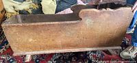 Side view of the antique pine cradle showing scalloped top edges and wear on the surface.