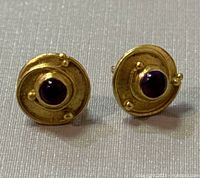 Front view of both earrings on neutral background showing round design and purple tourmaline centers