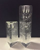 Frontal view of two triangular glass candlestick holders showing height difference and internal bubble texture.