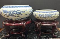 Front view of two blue and white porcelain bowls with dragon motifs on wooden stands under good lighting.