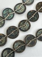 Close-up showing details of individual Feng Shui coins with Chinese characters and natural patina.