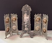 Photo of three vintage style metal photo frames including two folding frames with embossed female portrait medallions and one tall single frame with floral scroll design and vintage lady photo inserted.