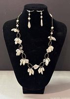 Full view of necklace and earrings set displayed on black bust showing design and length.