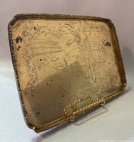 Angled side view of solid brass hand etched tray showing detailed Asian-inspired design and minor wear