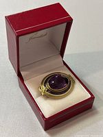 Brooch displayed in red jewelry box at angle showing stone and setting