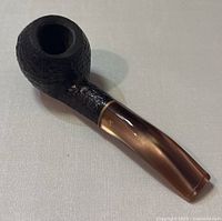 Side angle photo showing the full pipe with textured bowl and translucent brown stem and gold band detail.