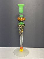 Front view of the tall green and multi-colored speckled art glass candlestick holder with frosted base.