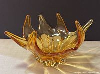 Side angle view showing amber amber-tinted Murano glass bowl with organic starburst design and multiple points.