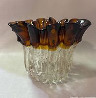 Front angle showing entire vase with ruffled amber rim and clear base on a white surface
