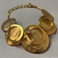 Front view of the Don Joyelli modernist bracelet showing layered circular gold-tone discs with rhinestones, lobster claw clasp, and chain extension.