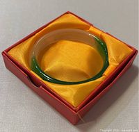 Natural Asian multicolor jade bangle in original red box with yellow satin lining.