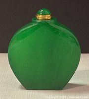 Front view of the green jade perfume/snuff bottle showing smooth polished surface and brass capped lid with jade cabochon.