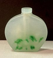 Front view of translucent jade perfume or snuff bottle showing white jade with green moss-like spots.